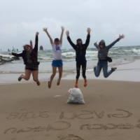 4 students jump for joy for Beach Cleanup